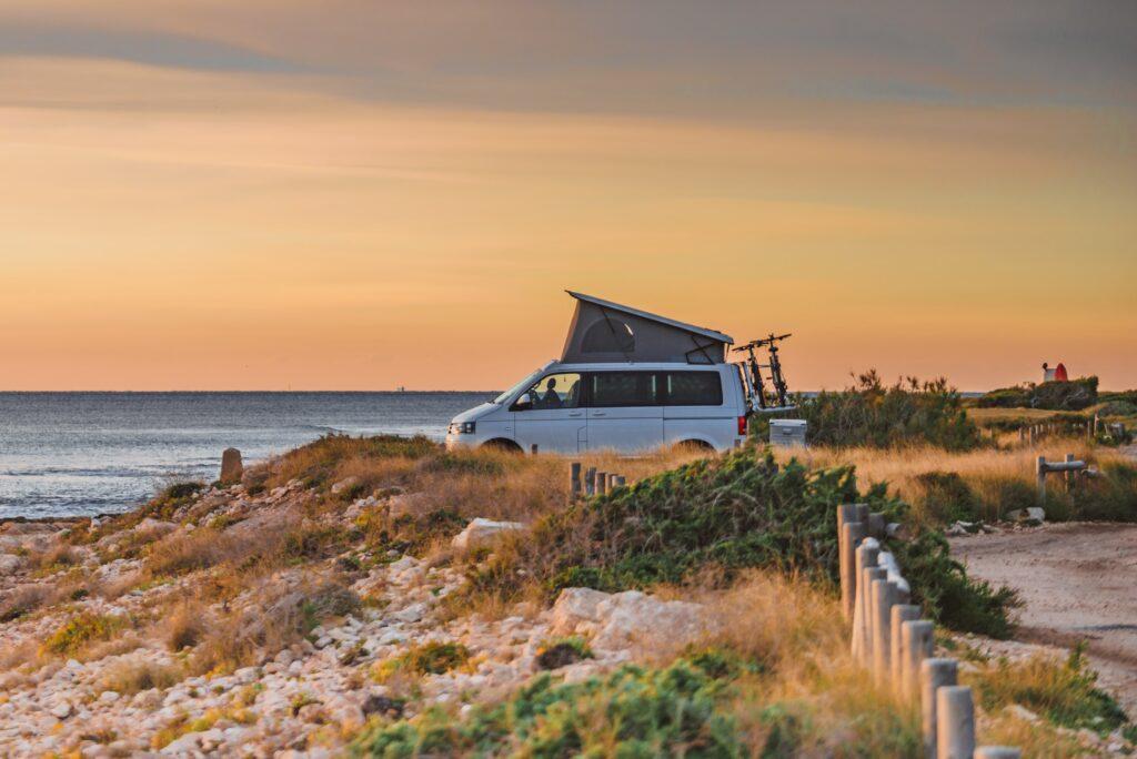 Pop top campervan parked on hilly beach landscape